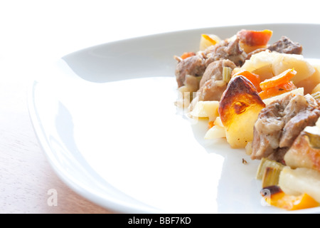 Abbondante carne e stufato di patate con carote e porri su un piatto bianco, pronto per essere gustato Foto Stock