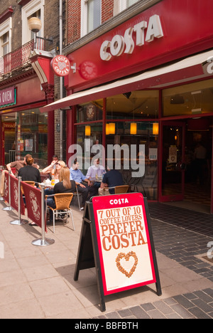 I clienti seduti all'aperto sotto il sole al di fuori di una costa coffee shop store bar in Norwich Norfolk Regno Unito Foto Stock