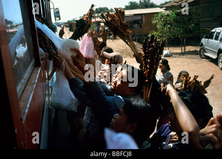 Strada locale i fornitori che offrono spuntini ai passeggeri di un autobus in viaggio da Savannakhet a Paxxe in Laos. Foto Stock