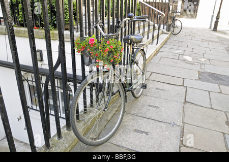 Onorevoli bike concatenati per ringhiere e decorato con fiori Queen Square Londra Inghilterra REGNO UNITO Foto Stock