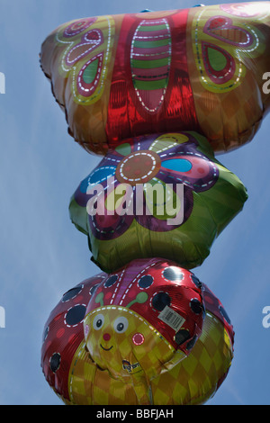Buon compleanno con i palloncini a faccia sorridente che fluttuano contro un cielo blu da vicino da sotto il formato verticale con vista frontale ad angolo basso negli Stati Uniti ad alta risoluzione Foto Stock