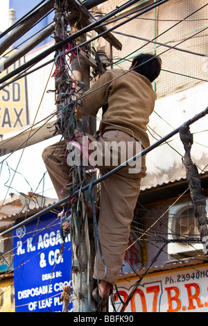 Uomo in un groviglio di cavi e fili nella Vecchia Delhi India Foto Stock