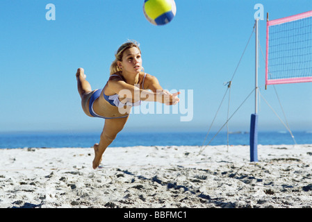 Femmina a giocare a beach volley, immersioni subacquee a sfera di cattura Foto Stock