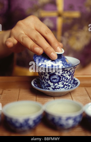 Mano collocando il coperchio della tazza da tè Foto Stock