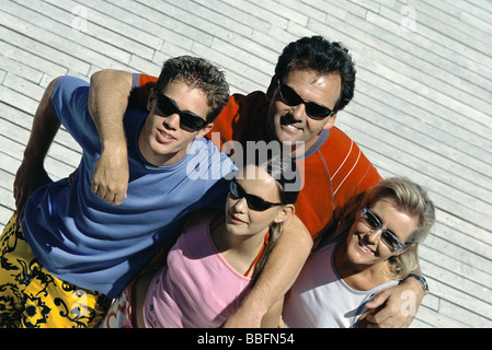 Famiglia con due bambini in piedi insieme sorridente in telecamera, ad alto angolo di visione Foto Stock