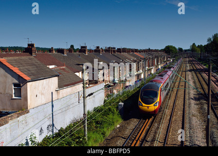 Una Vergine Pendolino che viaggiano attraverso l'Allerton sobborghi di Liverpool a fianco di case a schiera. Foto Stock