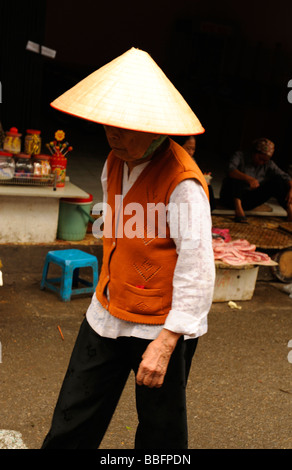 Il vietnamita old Lady indossando il tradizionale conehat passeggiando nel quartiere vecchio, Hanoi, Vietnam. Foto Stock