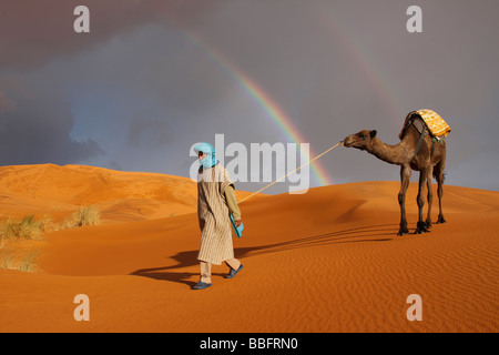 Africa, Nord Africa, Marocco deserto del Sahara, Merzouga Erg Chebbi, Berber Tribesman cammello leader, Rainbow nel deserto Foto Stock