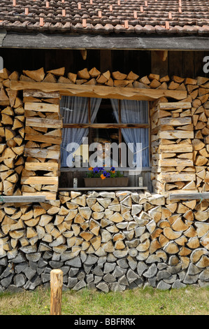 Legna da ardere accatastati intorno a un fienile con un manichino nella finestra, Mittenwald, Baviera, Germania Foto Stock
