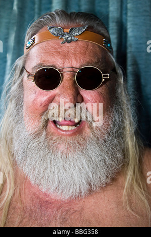 Ridendo vecchio rocker mancanti di denti frontali, i capelli lunghi e la barba, occhiali da sole e con archetto Foto Stock