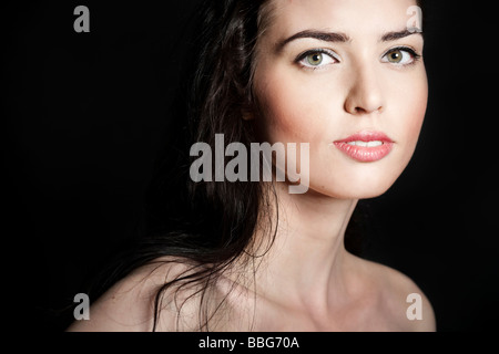 Ritratto di una giovane dai capelli scuri donna di fronte a uno sfondo nero Foto Stock