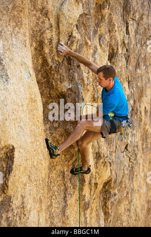 Scalatore risale una ripida roccia sbalzo. Foto Stock