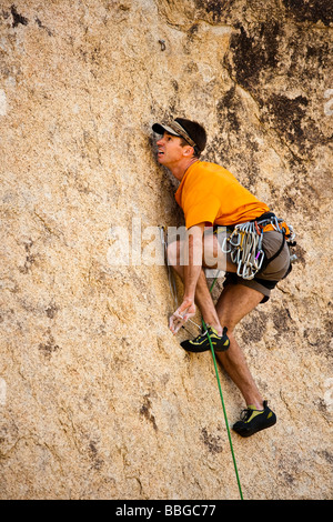 Scalatore risale una ripida roccia sbalzo. Foto Stock