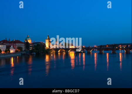 Vista della città attraverso il fiume Moldava con il ponte Carlo e la chiesa di San Francesco al crepuscolo, Praga, Repubblica Ceca Foto Stock