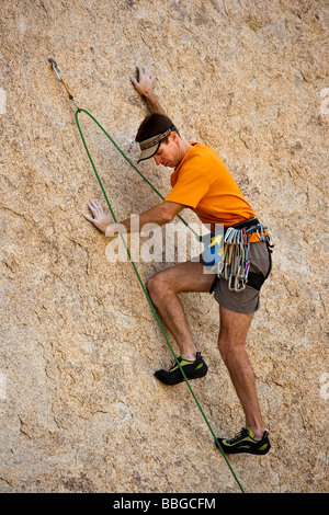 Scalatore risale una ripida roccia sbalzo. Foto Stock