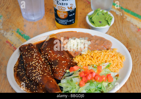 Enchiladas di pollo con una mole poblano e salsa di riso e fagioli con formaggio e un ordine di guacamole. Foto Stock