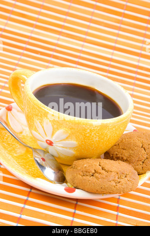 Close up i cookie e la tazza con il caffè sul bambù panno della tabella Foto Stock
