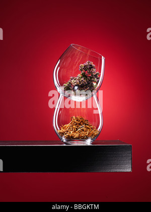 Le spezie in vetro su legno di noce con ripiano profondo rosso sfondo spotlit Foto Stock