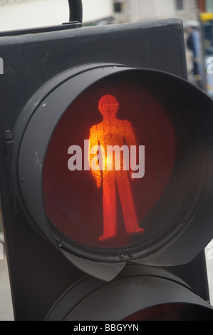 Una fotografia di un segno di arresto su un semaforo con un palo della luce, che mostra una figura umana illuminata in rosso. Foto Stock