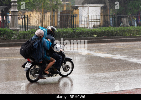 3 persone a cavallo scooter su strada bagnata in heavy rain, 'Ninh Binh', Vietnam, [Southeast Asia] Foto Stock