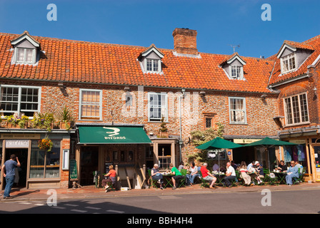 I clienti seduti fuori nel sole bere il tè e caffè a Byfords delicatessen restaurant cafe in Holt Norfolk Regno Unito Foto Stock