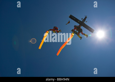 Skydivers sono battenti con testa in alto con un tubo di aria in vi mani e uscendo da un piano con un sacco di divertimento insieme. Foto Stock