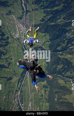 Paracadutista in tandem ottenere riprese da un cameraman nel cielo blu su un bel paesaggio con neve montagne e laghi. Foto Stock