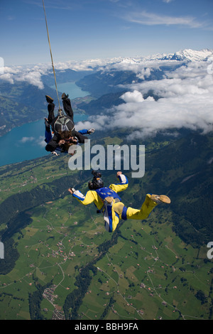 Paracadutista in tandem ottenere riprese da un cameraman nel cielo blu su un bel paesaggio con neve montagne e laghi. Foto Stock