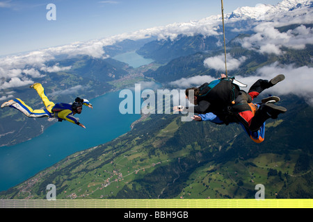 Paracadutista in tandem ottenere riprese da un cameraman nel cielo blu su un bel paesaggio con neve montagne e laghi. Foto Stock