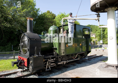 Ingegnere di locomotiva riempie la contessa motore a vapore con acqua da una torre di acqua su una ferrovia a scartamento ridotto di attrazione turistica Foto Stock