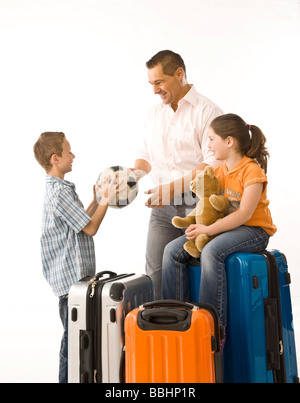 Padre di due figli, circondato da valigie Foto Stock