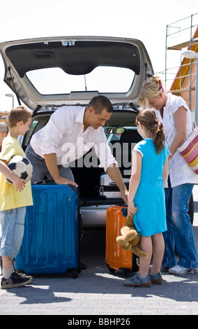 Famiglia stivare le valigie in auto Foto Stock