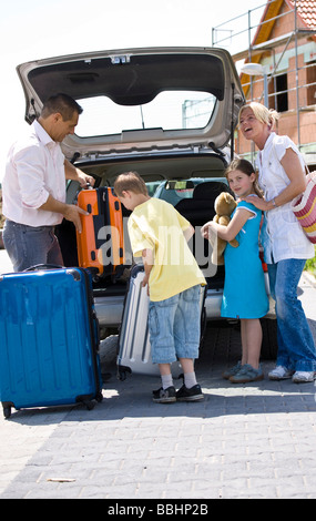 Famiglia stivare le valigie in auto Foto Stock