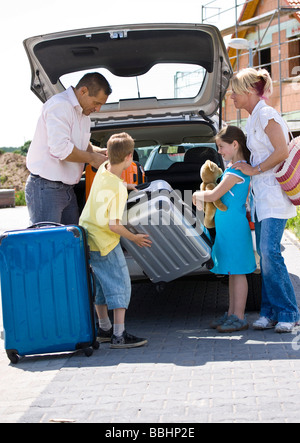 Famiglia stivare le valigie in auto Foto Stock