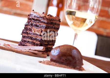 Flourless spugna di cioccolato dolce fatto con mousse al cioccolato fondente pepe nero creme anglaise servita con un cucchiaio di cioccolato Foto Stock