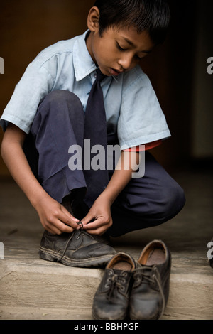 Pokhara, Nepal; ragazzo orfano mettendo sulle scarpe Foto Stock