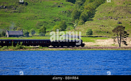 Giacobita treno a vapore con il Loch Eilt in primo piano, Lochaber, Scotland, Regno Unito, Europa Foto Stock