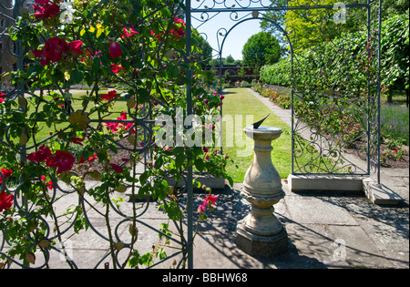 Ferro battuto trellis con rose e una meridiana in giardini privati di Lambeth Palace London REGNO UNITO Foto Stock