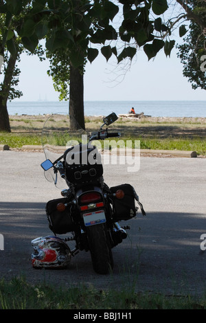 Giovane coppia seduta sulla spiaggia in riva al mare nel parco cittadino viaggio attivo vista posteriore negli Stati Uniti Stati Uniti Lago Erie grandi Laghi verticale ad alta risoluzione Foto Stock