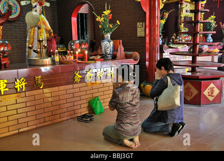 Due donne inginocchiarsi e pregare di fronte a un altare di Buddha, Quan Am Pagoda, Ho Chi Minh City, a Saigon, Vietnam, sud-est asiatico Foto Stock