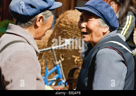 Due donne della tribù Naxi godendo di una barzelletta privato al mercato di Lijiang, Yunnan, Cina Foto Stock