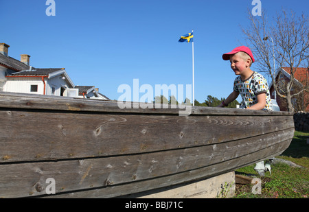 Giovane ragazzo giocando nella vecchia barca a terra Foto Stock