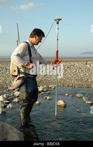 Tecnico Hydology impresa fiume misurazioni a un piccolo fiume che entra in mare nel Galles del Nord Regno Unito Foto Stock