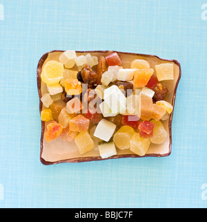 Un assortimento di frutta secca tagliata a quadrati per la stagionatura in un quadrato vaso in ceramica su sfondo rétro Foto Stock