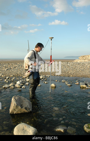 Idrologia tecnico impresa fiume misurazioni a un piccolo fiume che entra in mare nel Galles del Nord Regno Unito Foto Stock