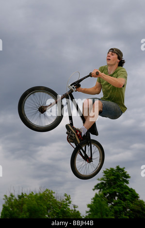 Bmx rider volare in aria contro una nube scura mentre si ascolta la musica di Toronto skate park Foto Stock