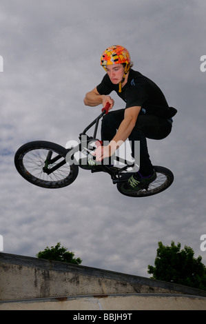 Smorfie bmx bike rider volare in aria facendo un'aria fuori dal piano portapaziente spostare fuori da un muro di cemento a Toronto in Canada Foto Stock