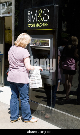 Una donna ottenere contanti da un Marks & Spencer bancomat ATM , M&S, Sidney Street, Cambridge, Regno Unito Foto Stock