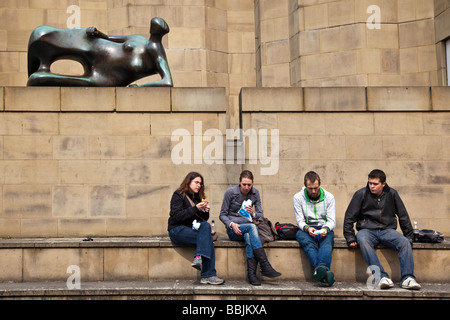 Gli studenti aventi il pranzo sotto la Henry Moore scultura donna reclinabile 80 al di fuori della galleria d'arte Leeds West Yorkshire Foto Stock