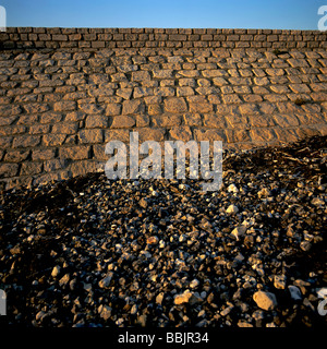 Muro di pietra lungo una spiaggia di ciottoli. Foto Stock